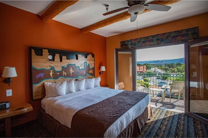 Hotel room at Southwest Inn Sedona with a bed featuring a wooden headboard and white pillows