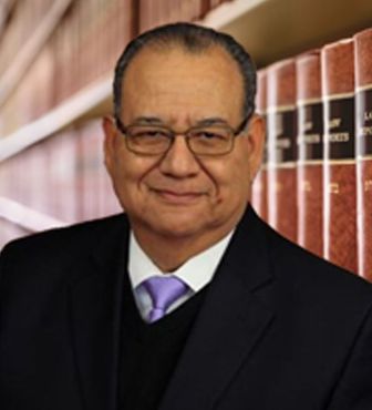 A woman is holding a baby and a cat is looking at the baby.