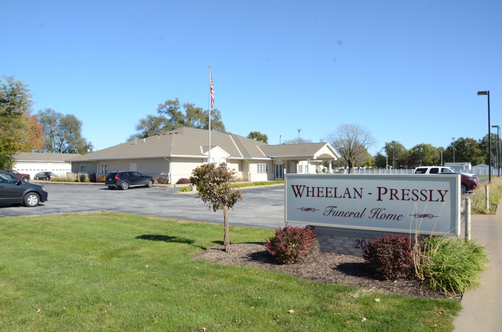 Whelan-Pressly Funeral Home exterior: one-story building with a sign and a lawn under a blue sky.
