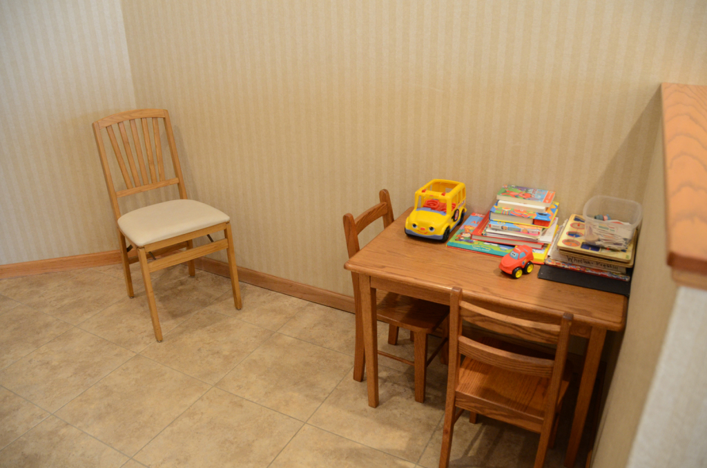 A small play area with a child's table and chairs, a regular chair, and toys.