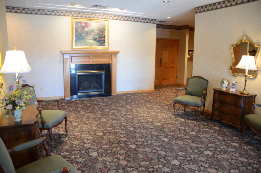 Formal room with fireplace, chairs, table, and floral carpet.
