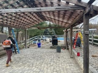 A group of people are walking under a wooden pergola.