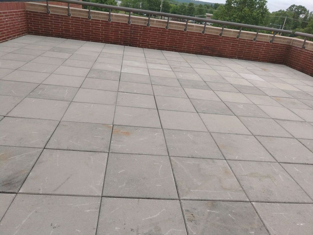 A rooftop with a brick wall and a tiled floor