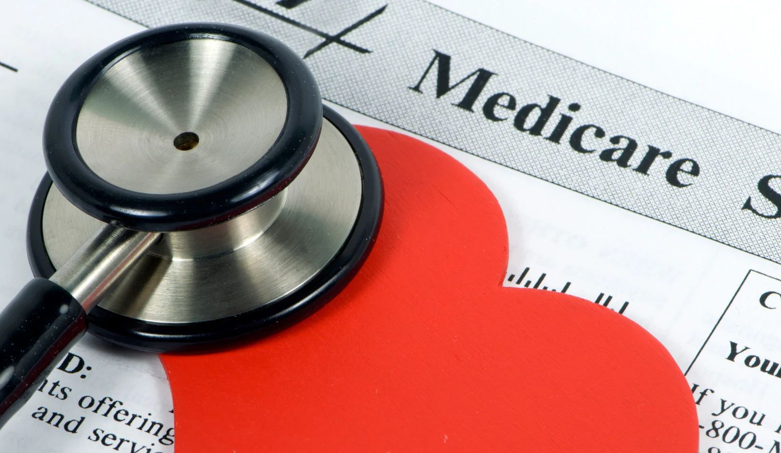 Stethoscope on a red heart, placed on top of a Medicare document.