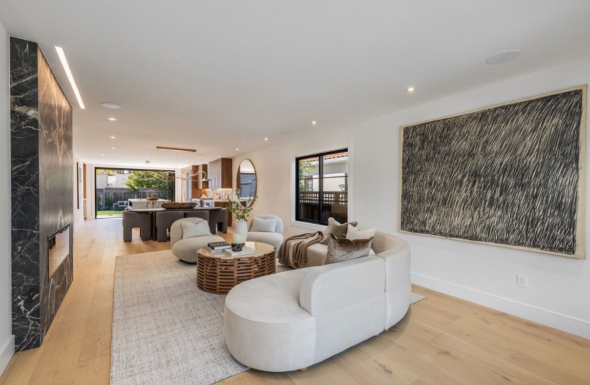 Modern living room with white curved sofa, rug, and black-and-white abstract art.