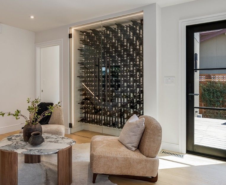 Wine cellar with dark metal racks, built into a wall, with seating and a marble table.