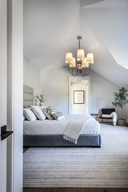 A bedroom with a large bed and a chandelier hanging from the ceiling.