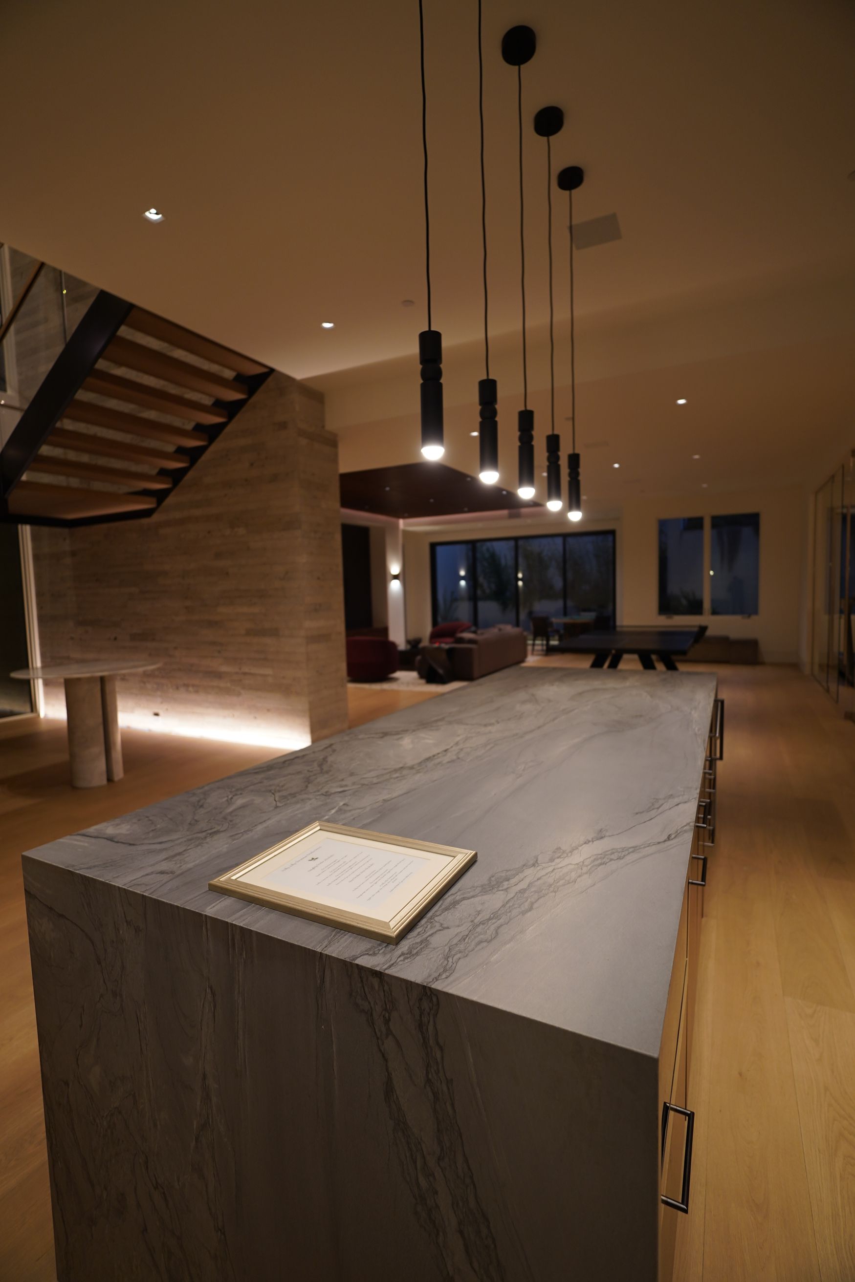A kitchen with a large island and a staircase in the background.