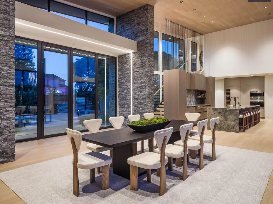 A large dining room with a table and chairs and a large window.