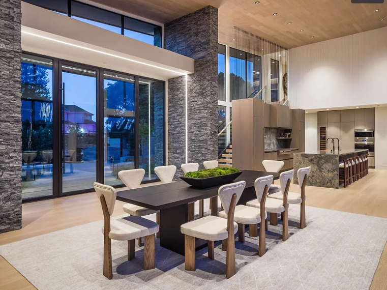 A large dining room with a table and chairs and a large window.