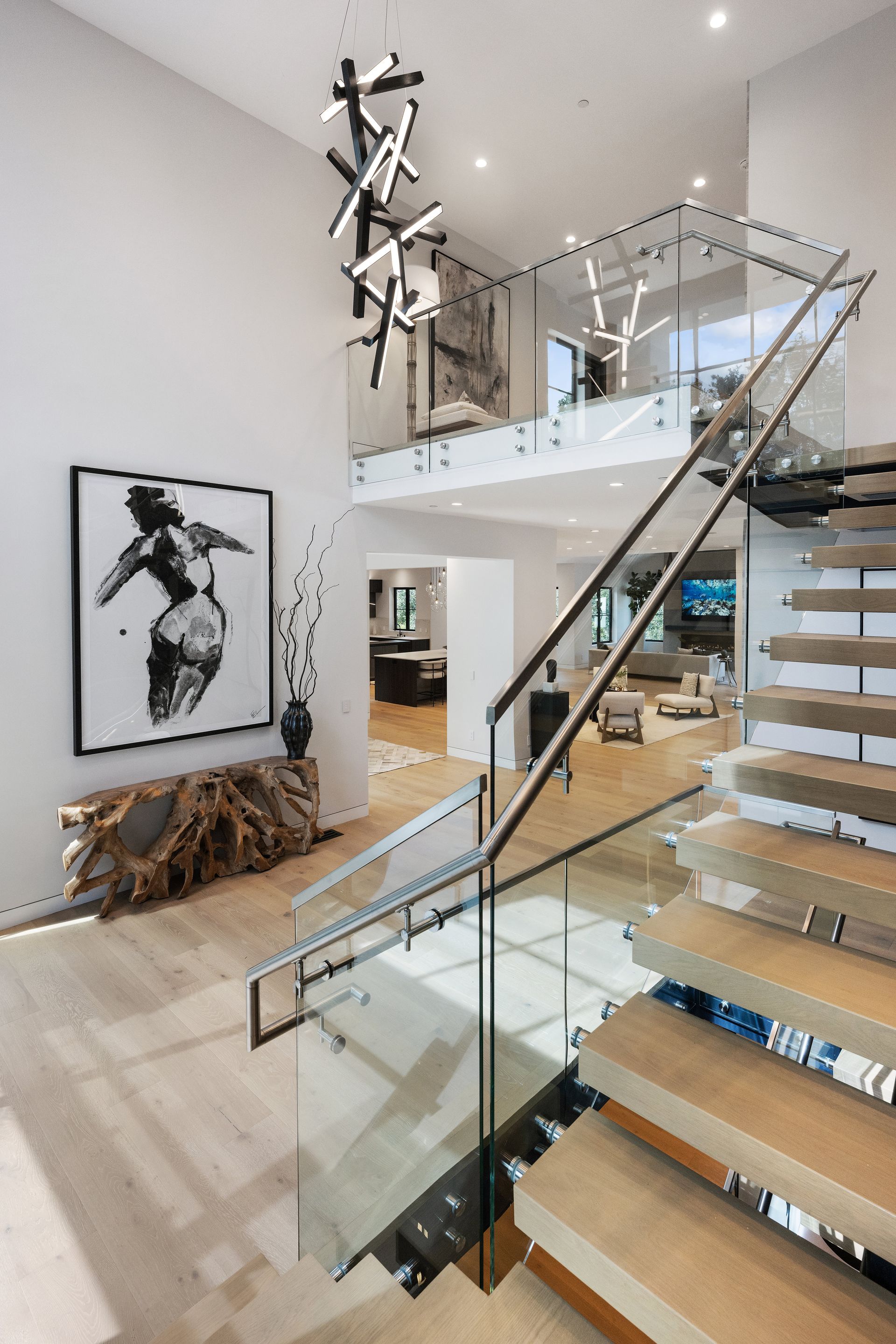 A staircase with a glass railing and a painting on the wall