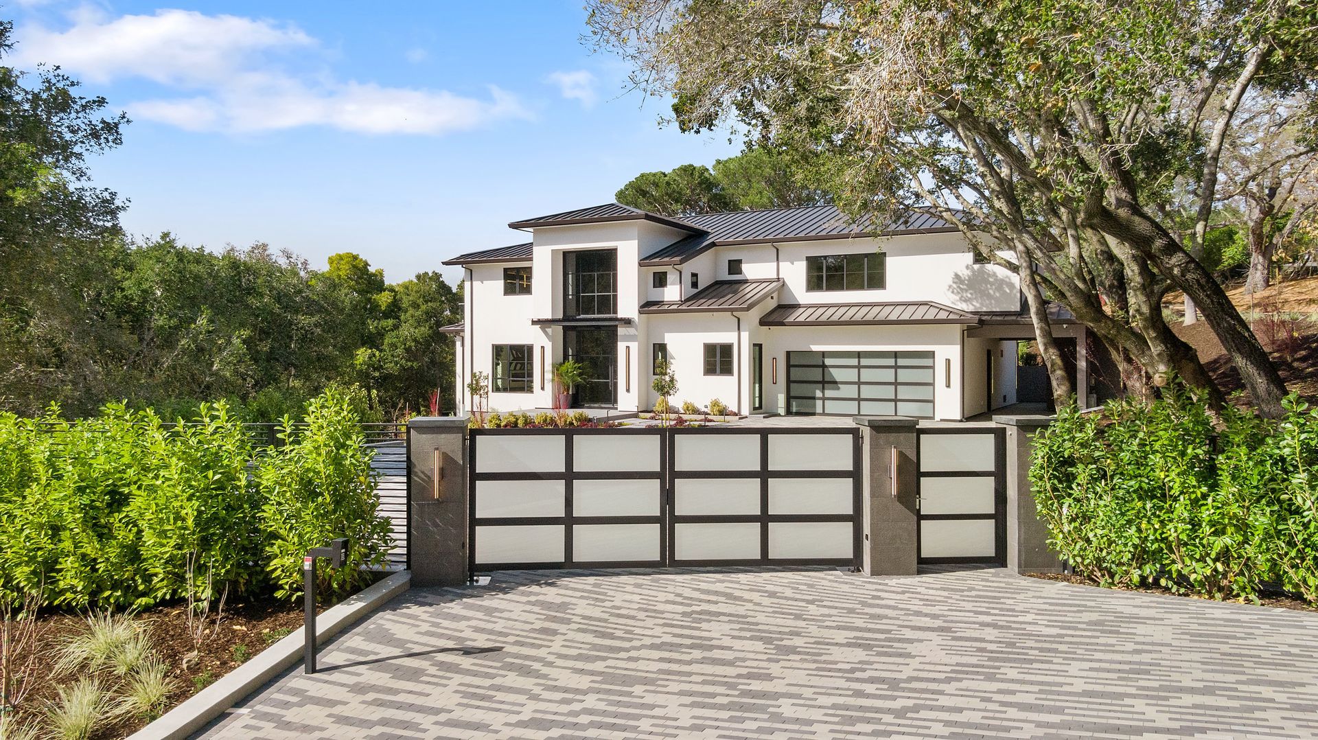 A large white house with a driveway leading to it surrounded by trees and bushes.