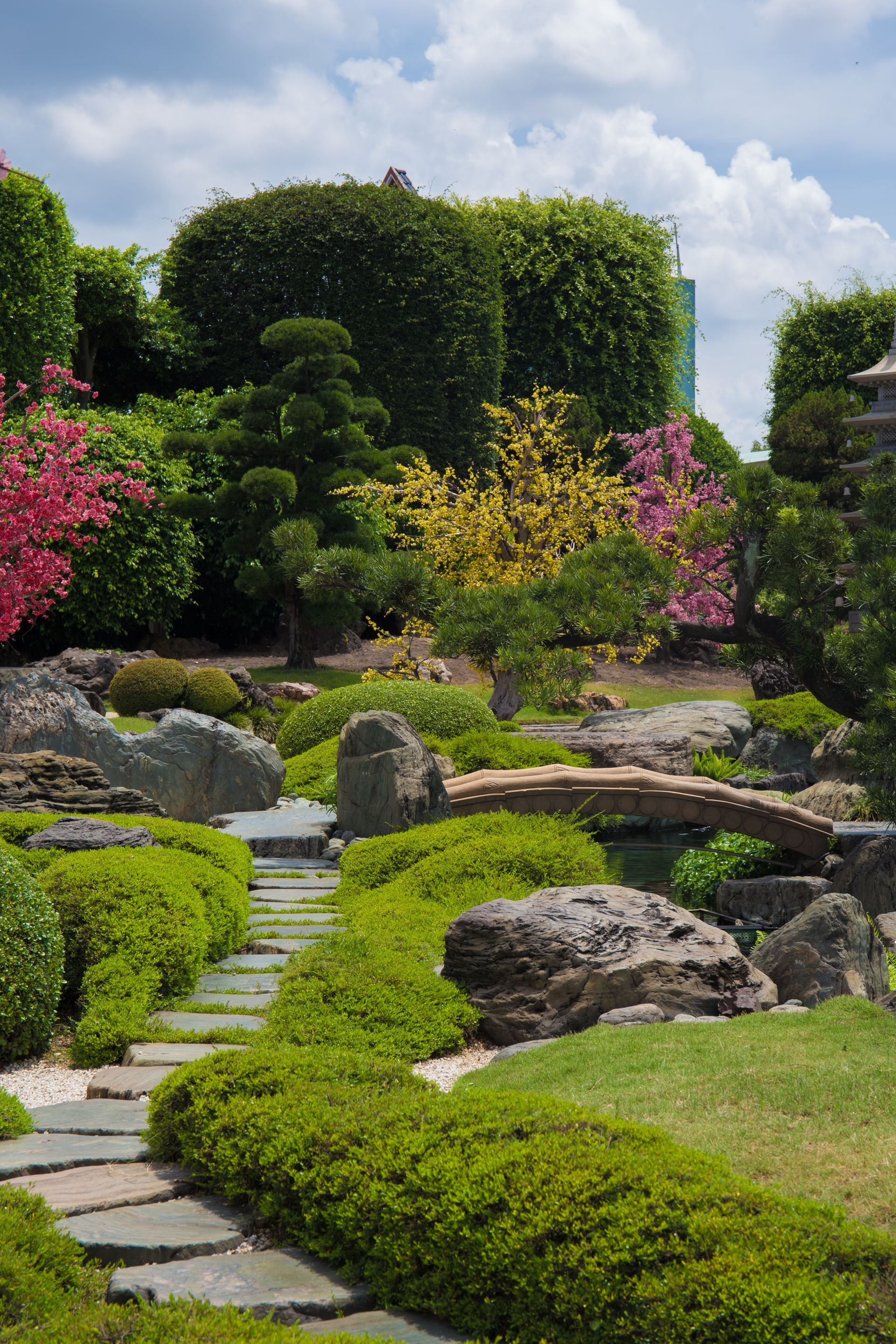 A stone path in a garden surrounded by trees and bushes