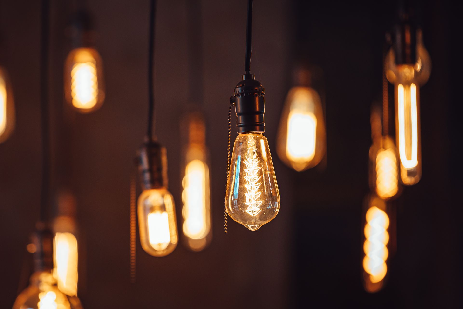 A bunch of light bulbs hanging from the ceiling in a dark room.