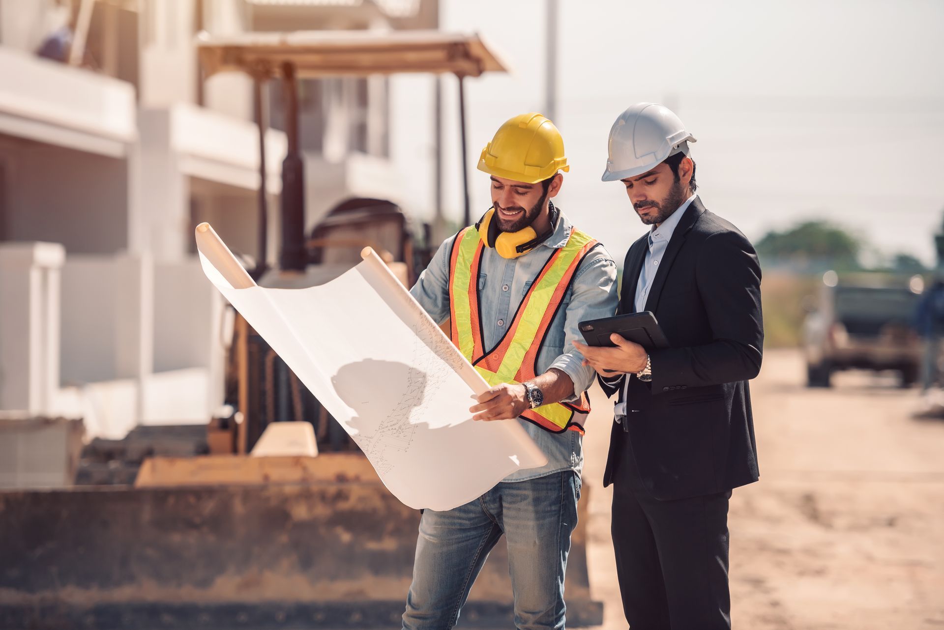 Two construction workers are looking at a blueprint on a construction site.