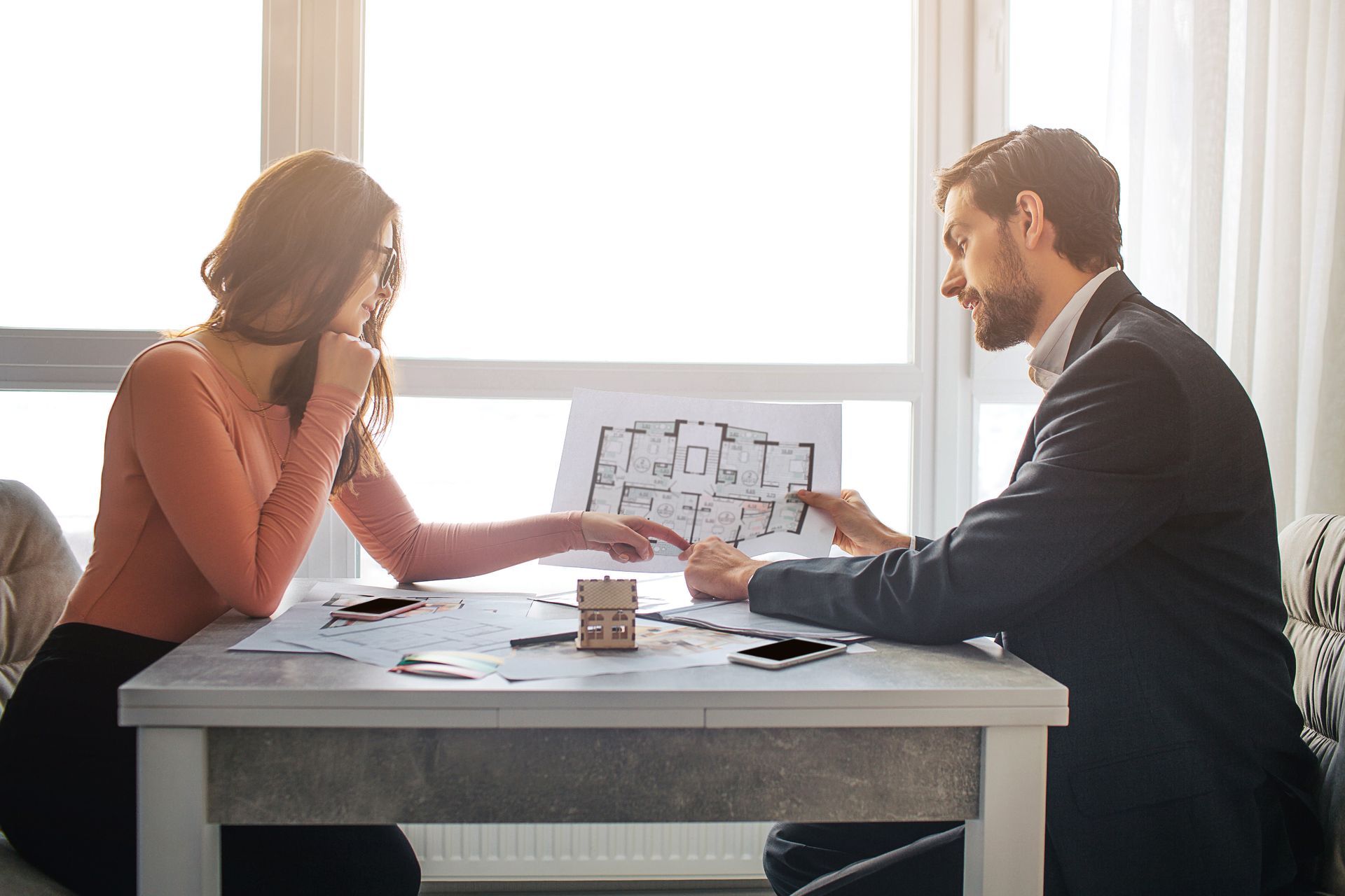 A man and a woman are sitting at a table looking at a house plan.