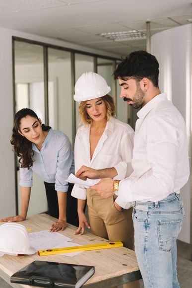 A group of people are standing around a table looking at a blueprint.