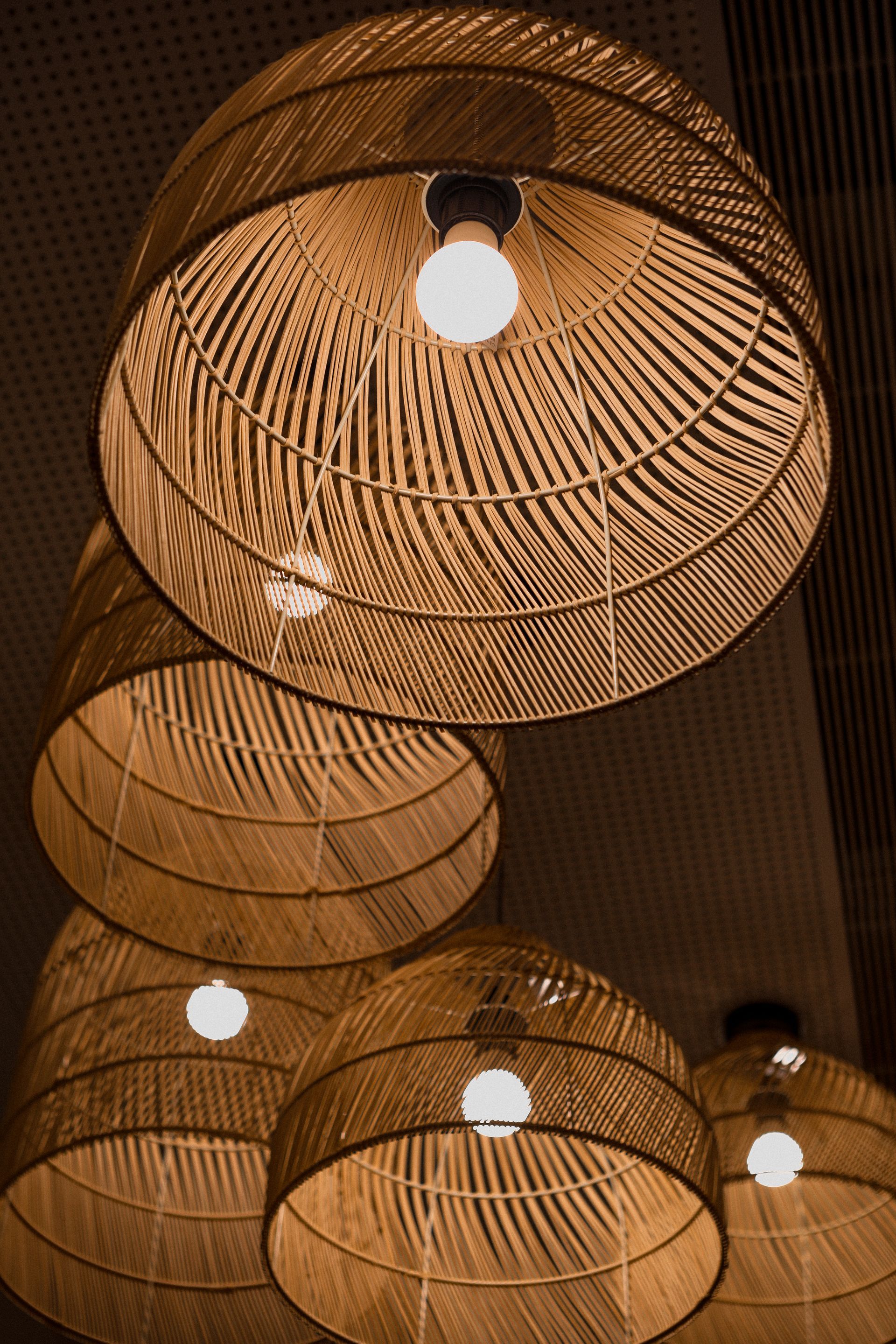 A bunch of wicker lamps are hanging from the ceiling.