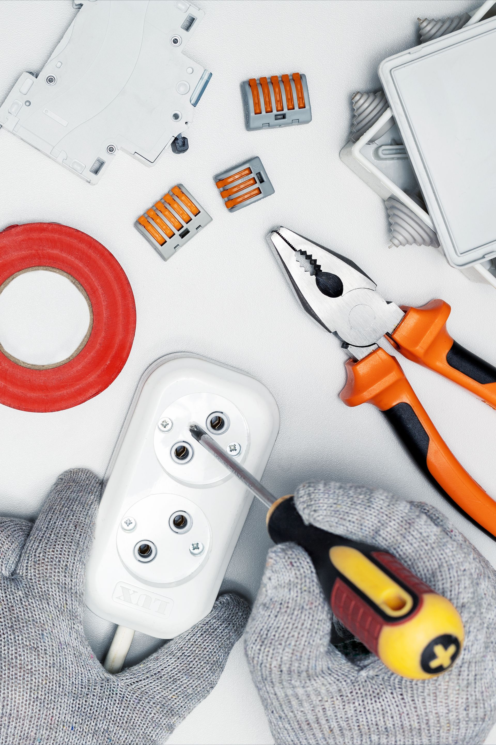 A person is holding a pair of pliers and a screwdriver.