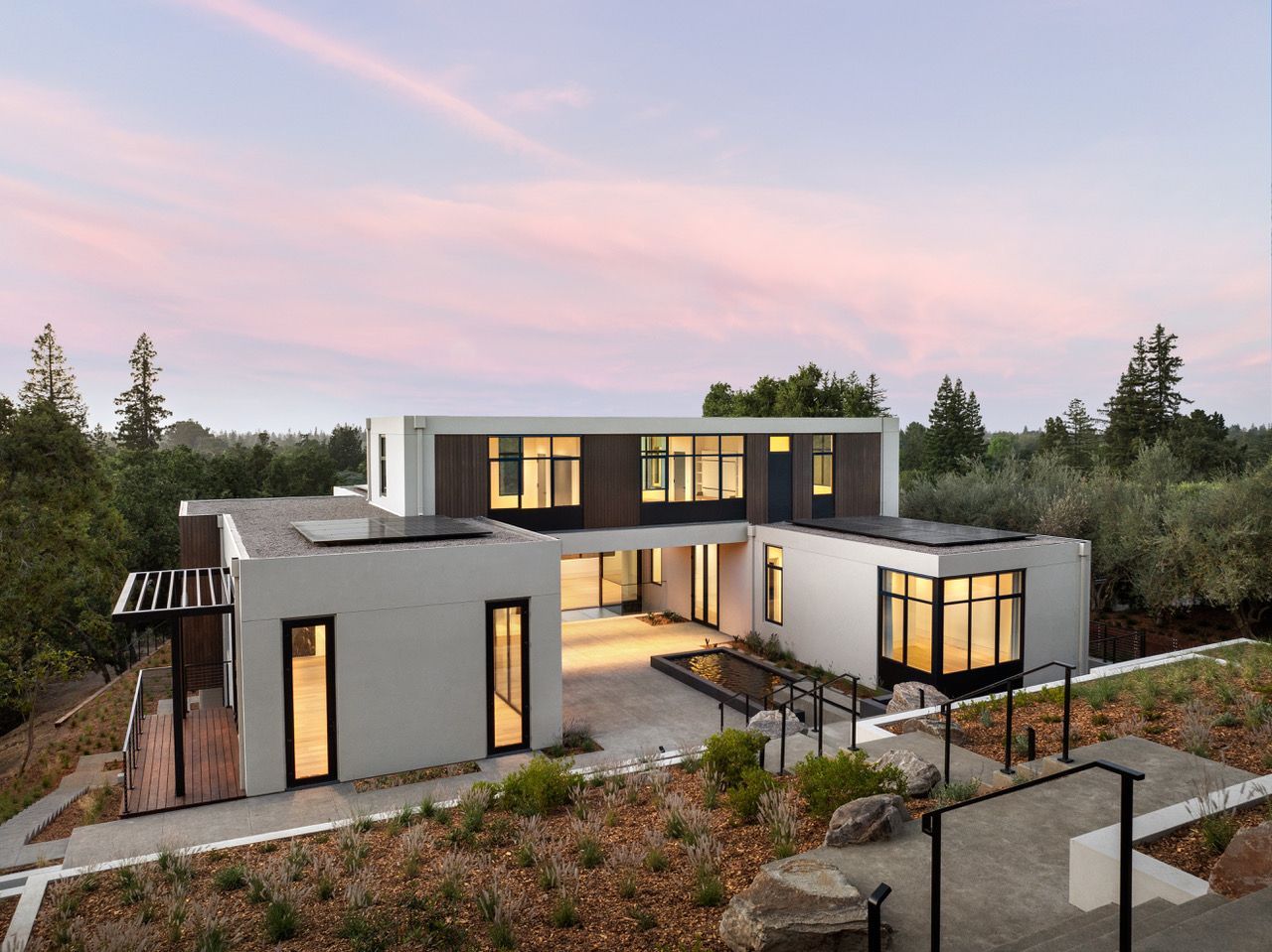 A large white house is sitting on top of a hill surrounded by trees.