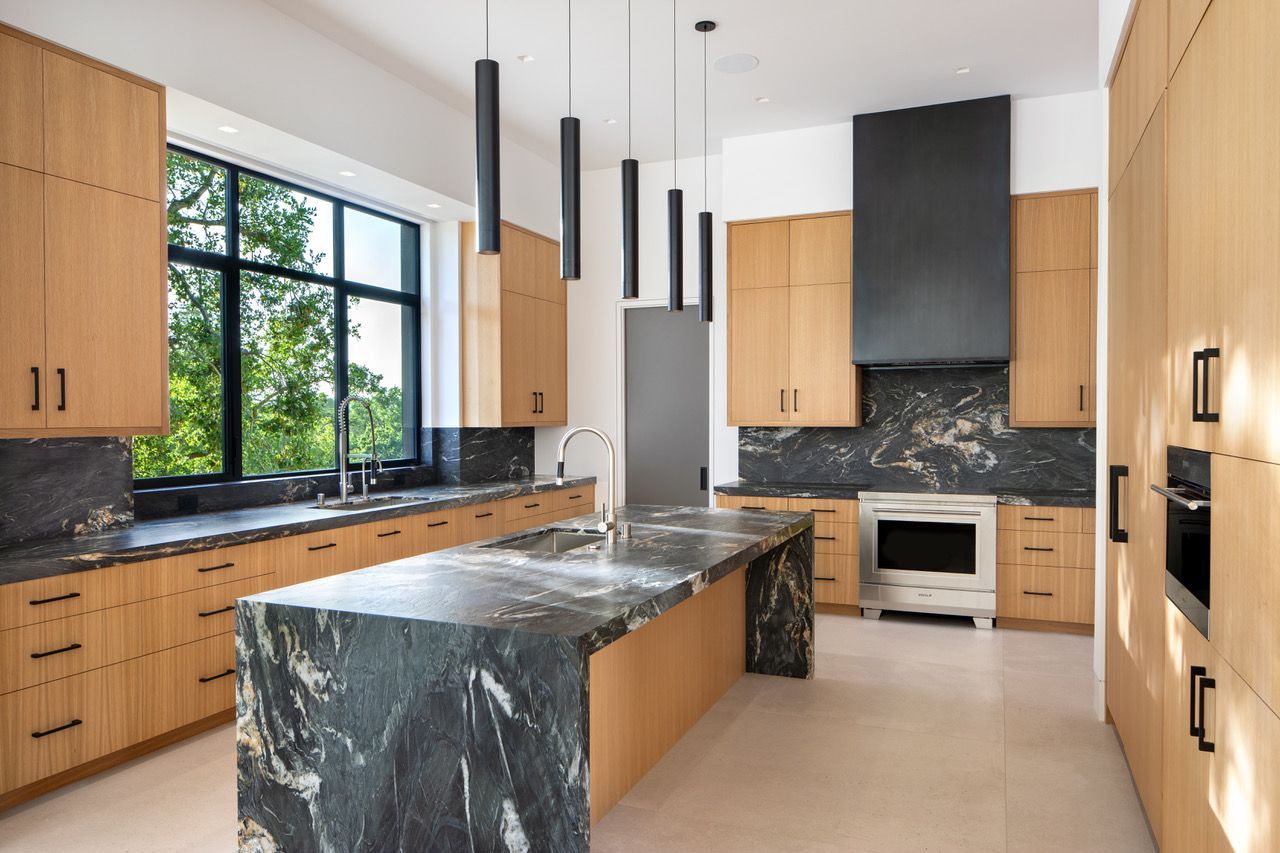 A kitchen with a large island in the middle and stainless steel appliances.