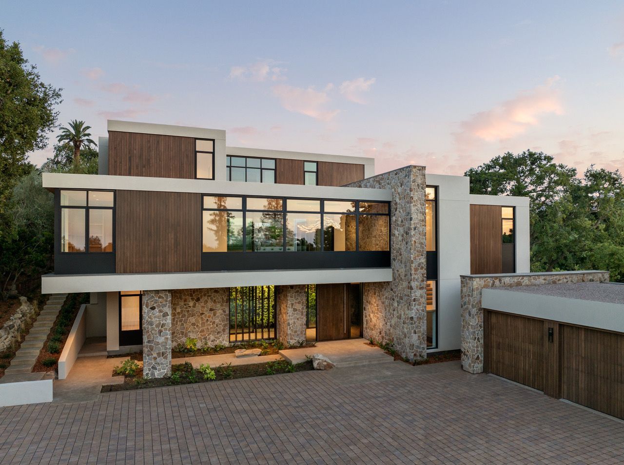 A large modern house with a brick driveway in front of it