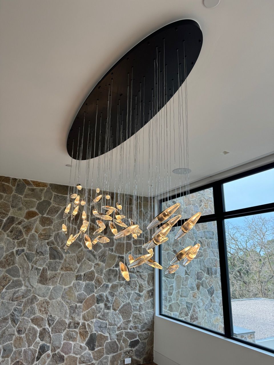A large chandelier is hanging from the ceiling in a room with a stone wall.