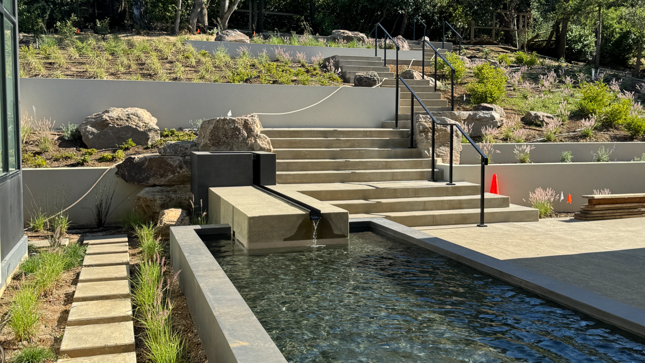 A swimming pool with stairs leading up to it and a waterfall in the background.