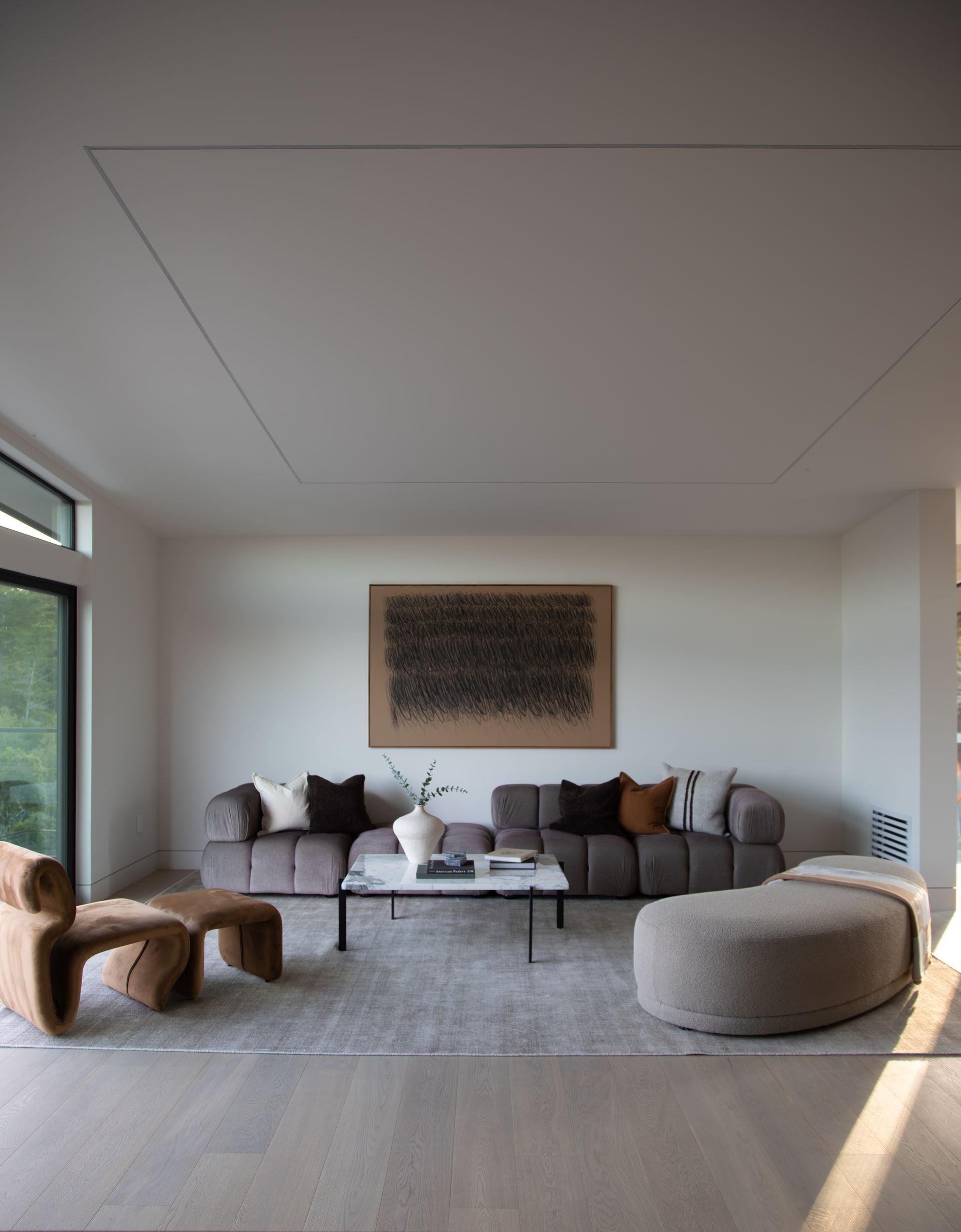 A living room with a couch , chair , coffee table and ottoman.