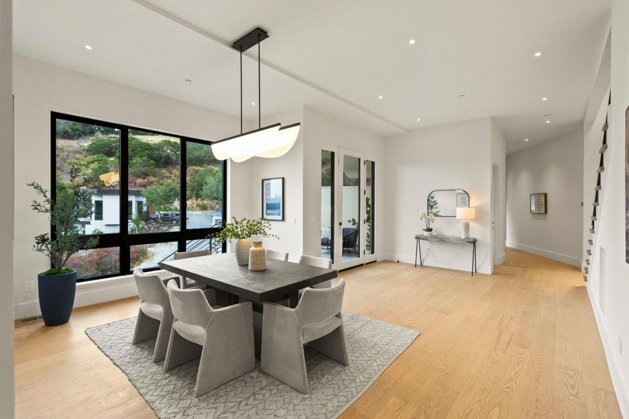 A dining room with a table and chairs and a large window.