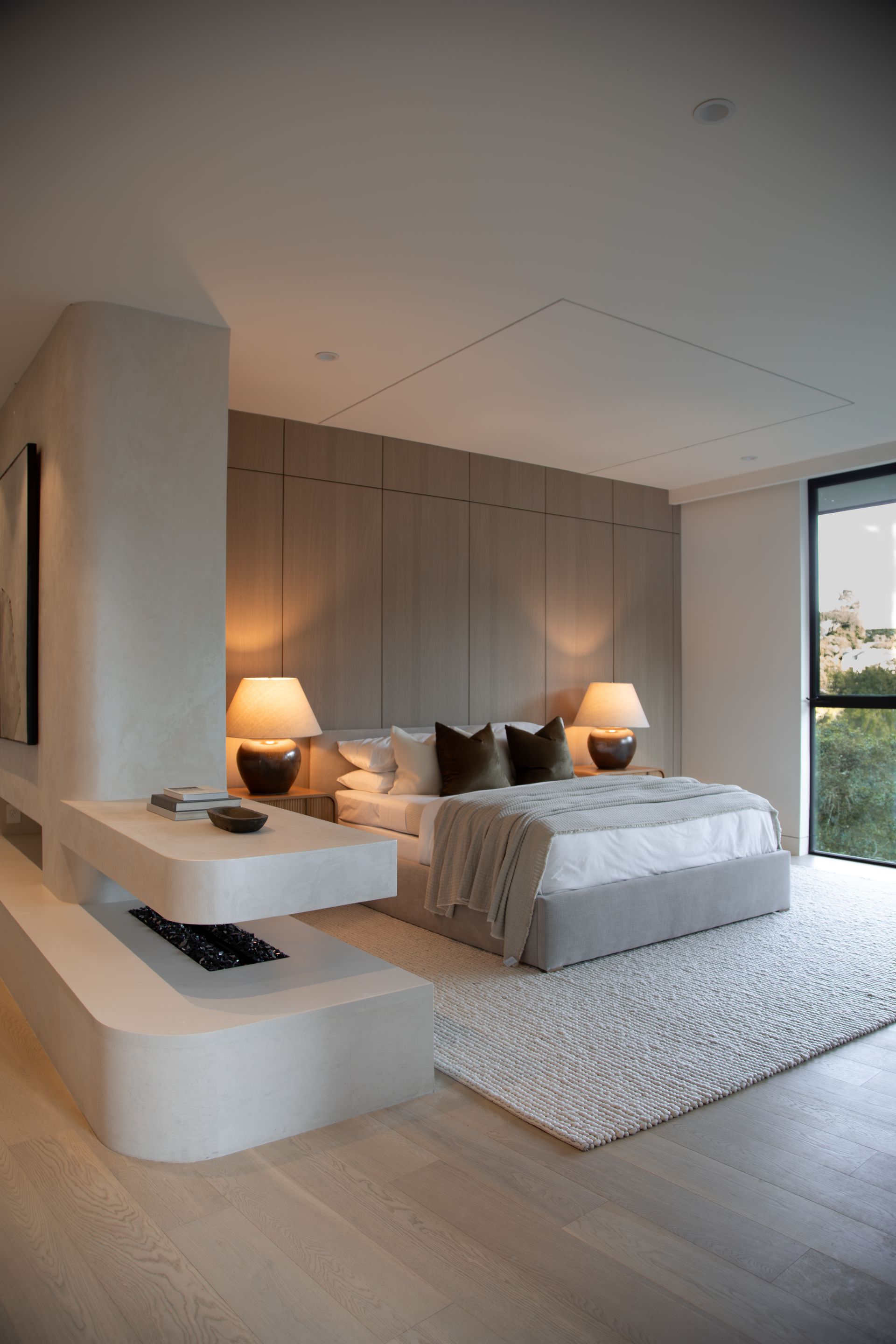 A bedroom with a large bed , lamps , and a fireplace.