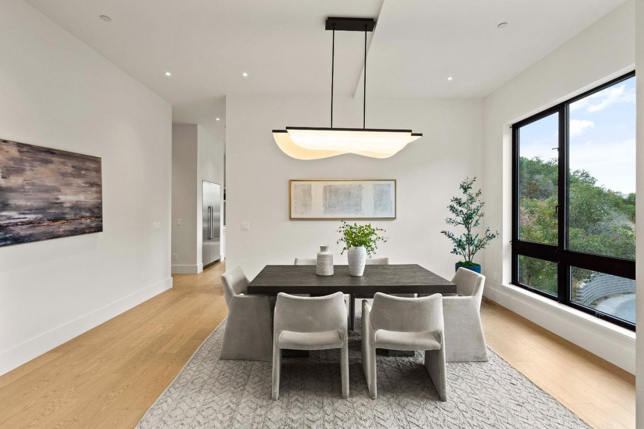 A dining room with a table and chairs and a large window.