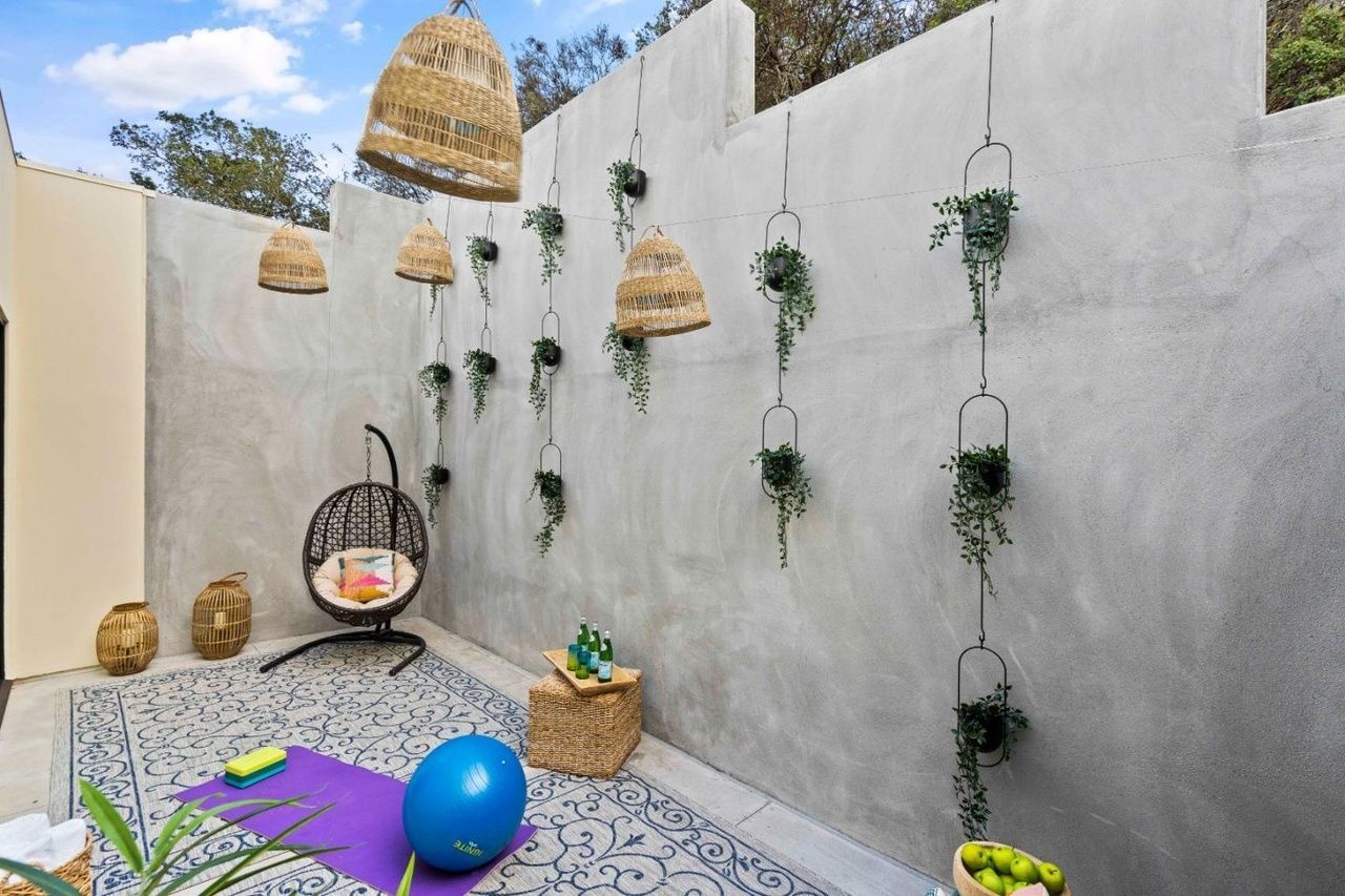 A patio with a yoga mat , a chair , and a blue ball.