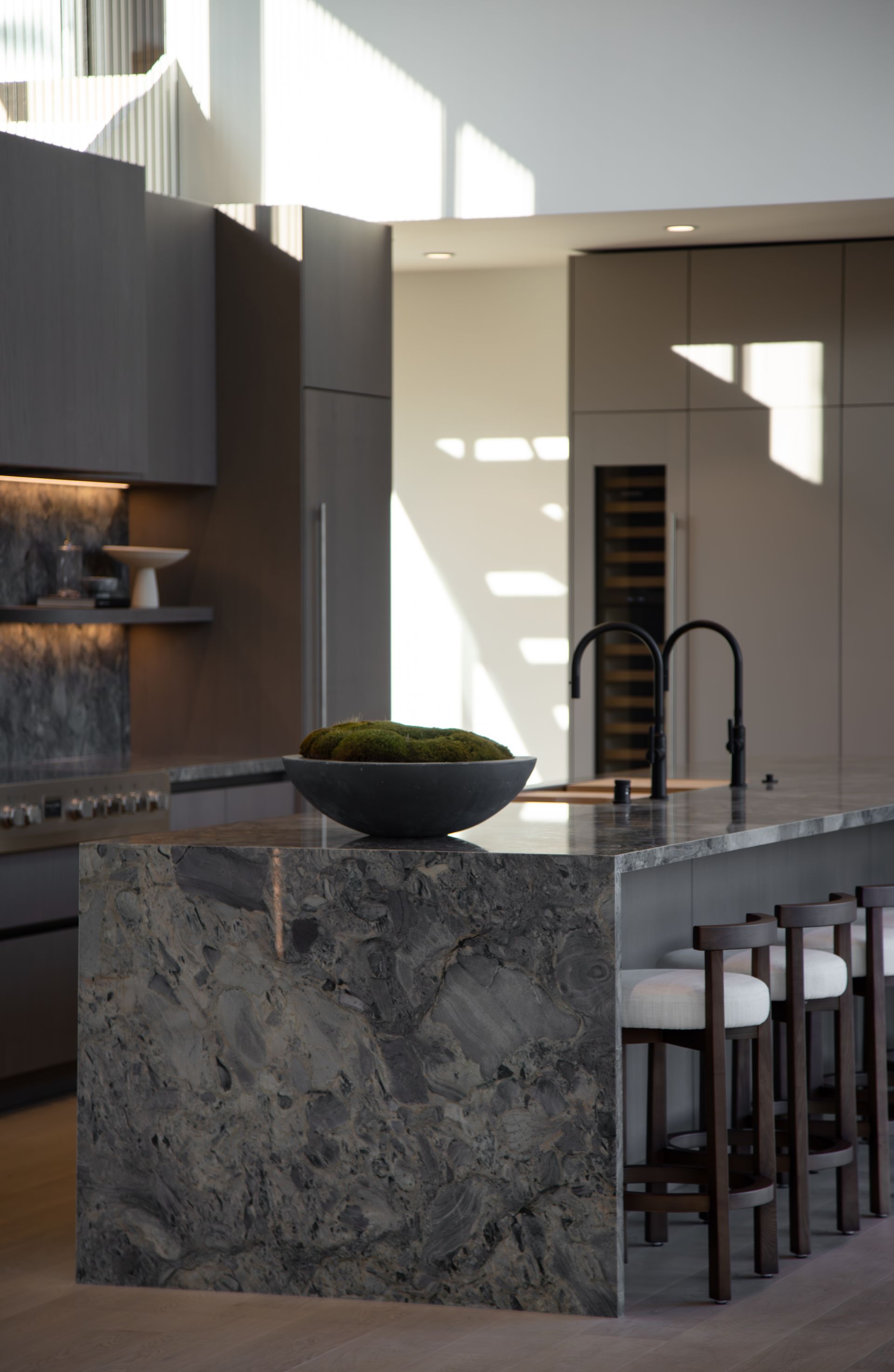 A kitchen with a large granite island and stools