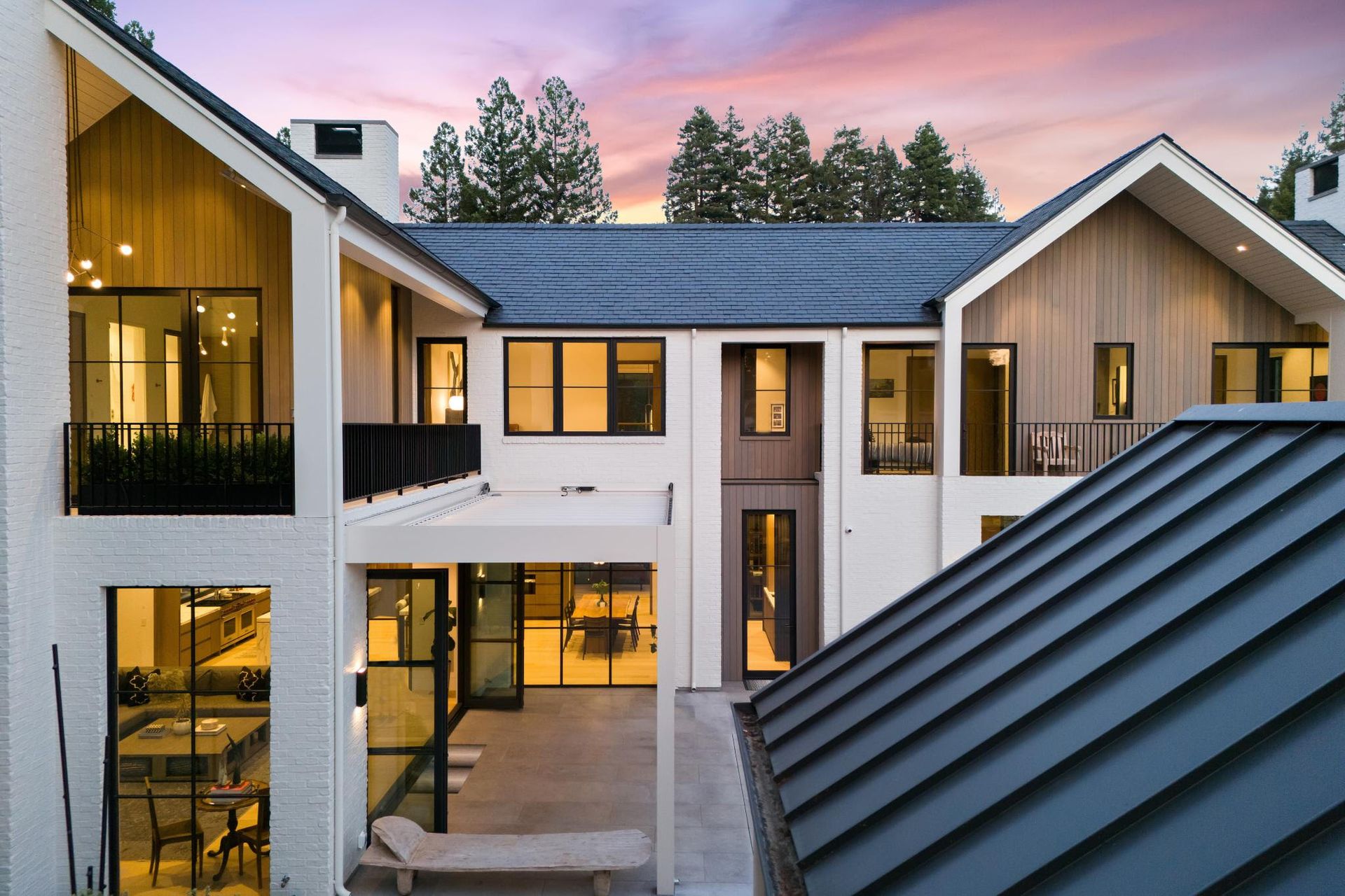 An aerial view of a large house with a blue roof at sunset.