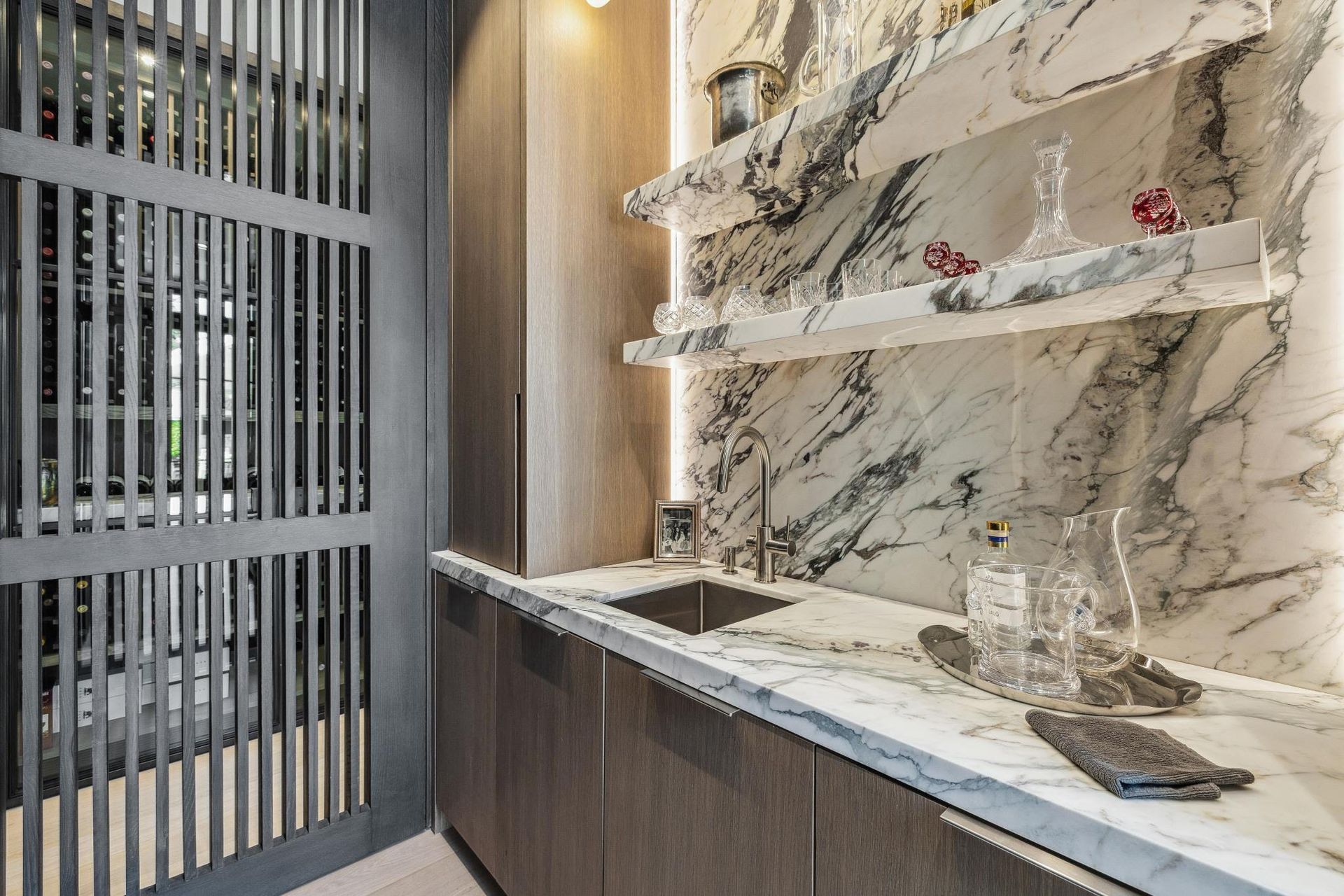 A kitchen with marble counter tops , a sink , and shelves.