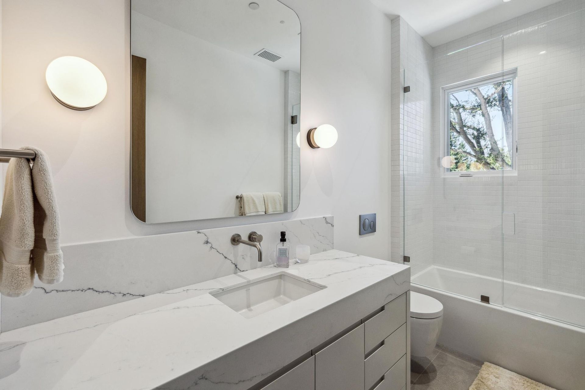 A bathroom with a sink , toilet , tub and mirror.