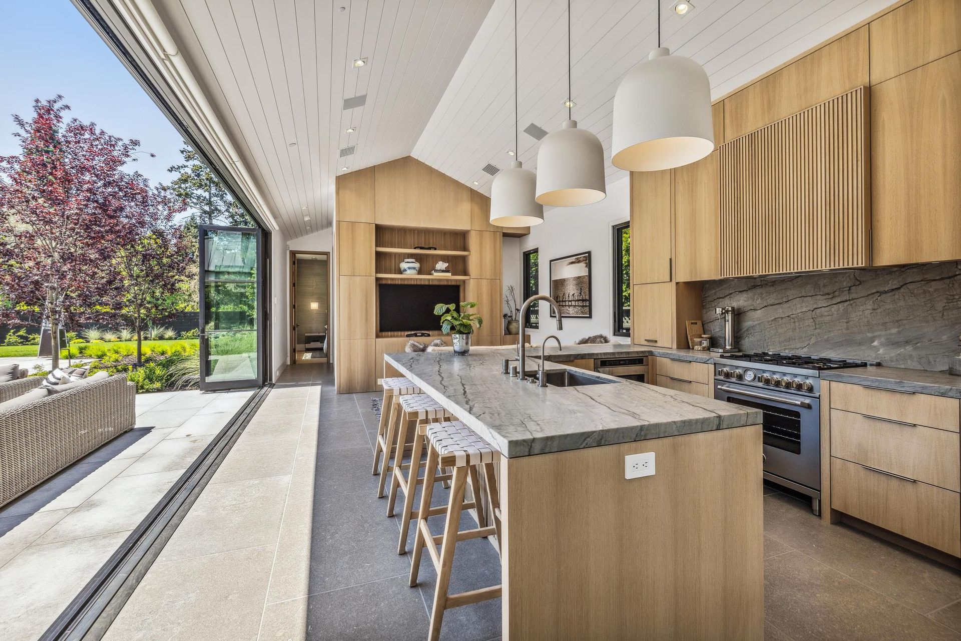 A kitchen with a large island , stools and a stove.
