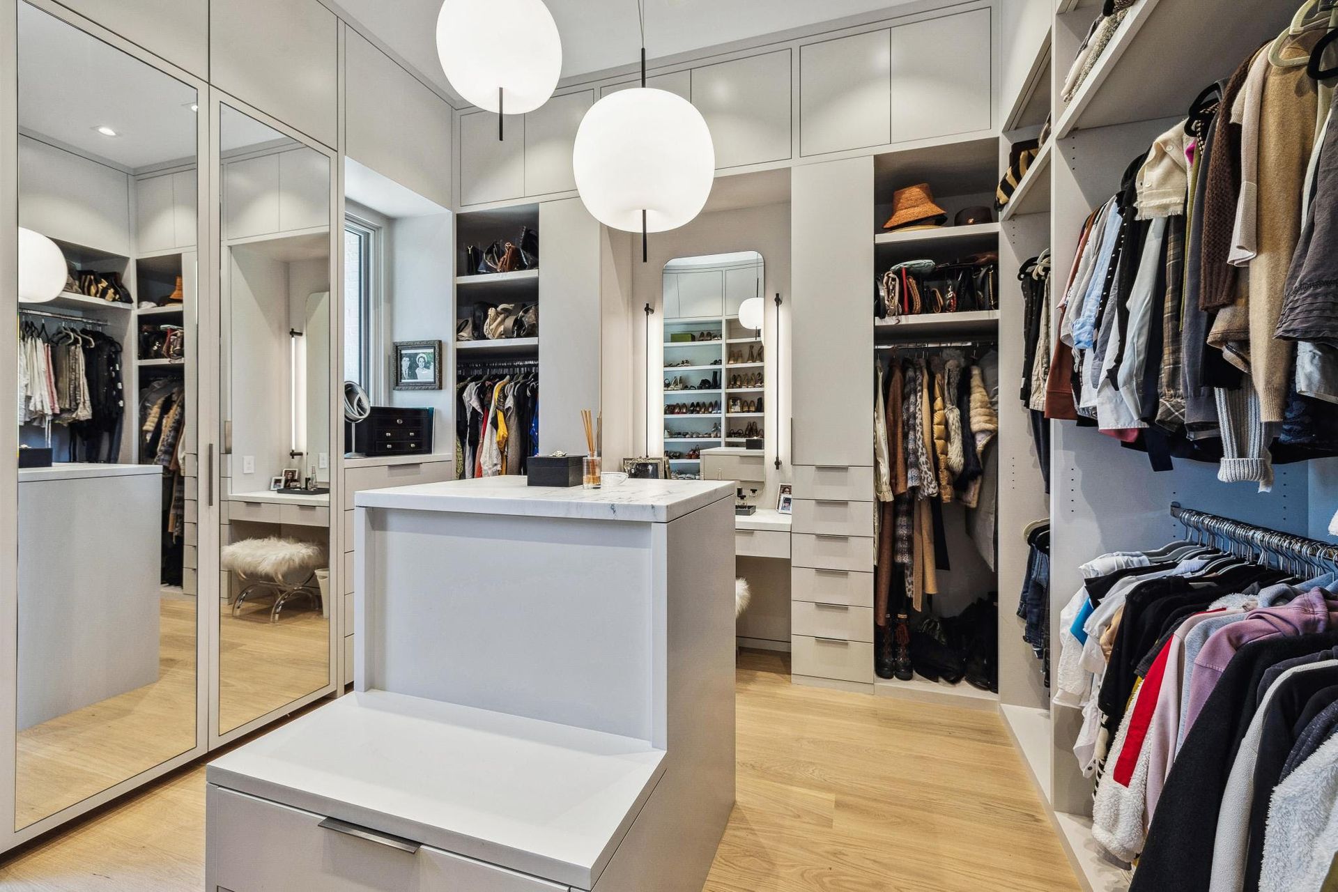 A walk in closet filled with lots of clothes and a vanity.