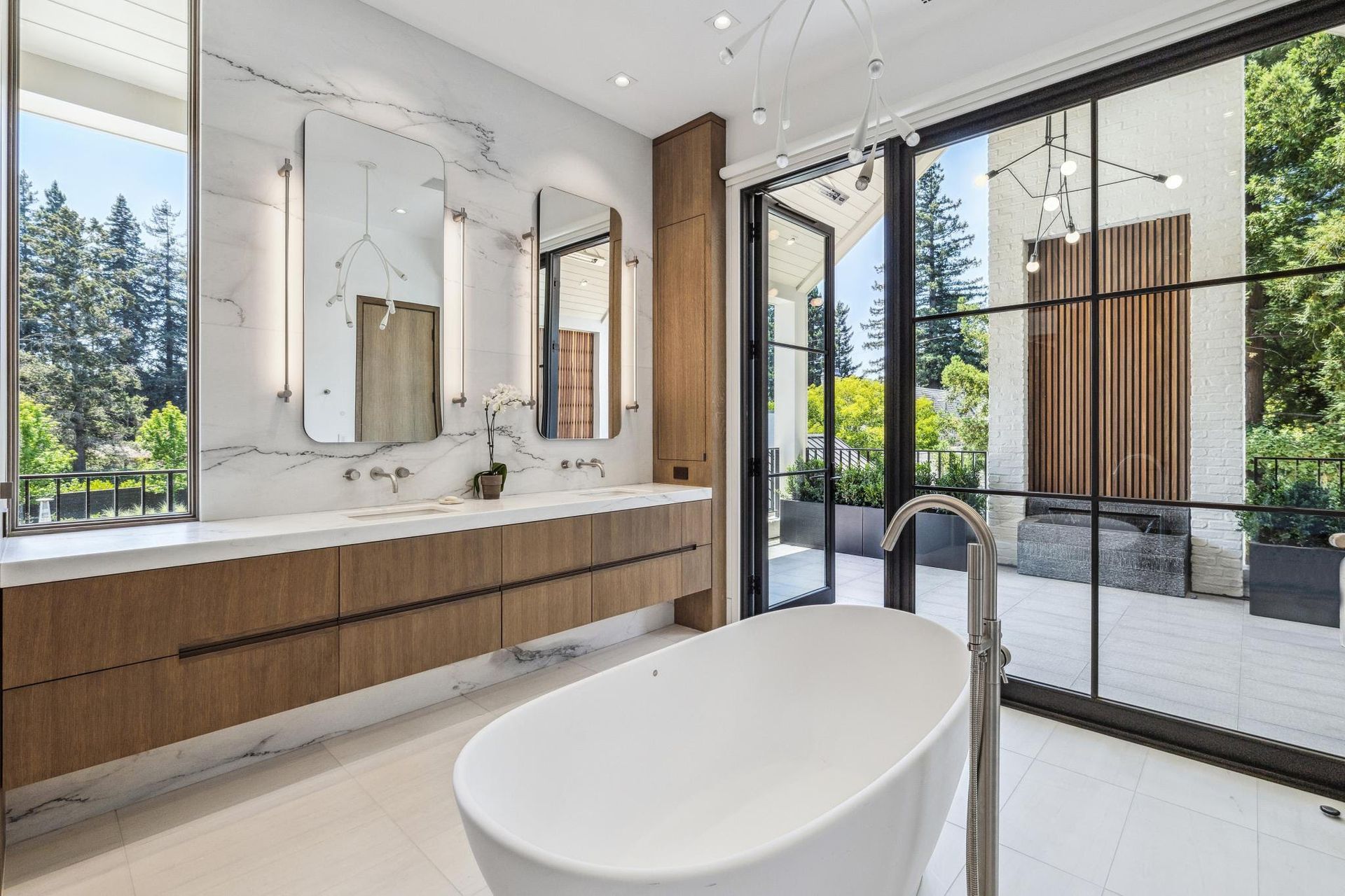 A bathroom with a tub , sinks , mirrors and sliding glass doors.