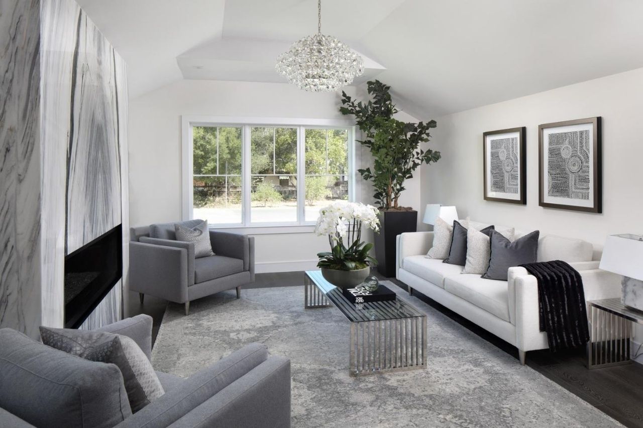 A living room with a couch , two chairs , a coffee table and a fireplace.