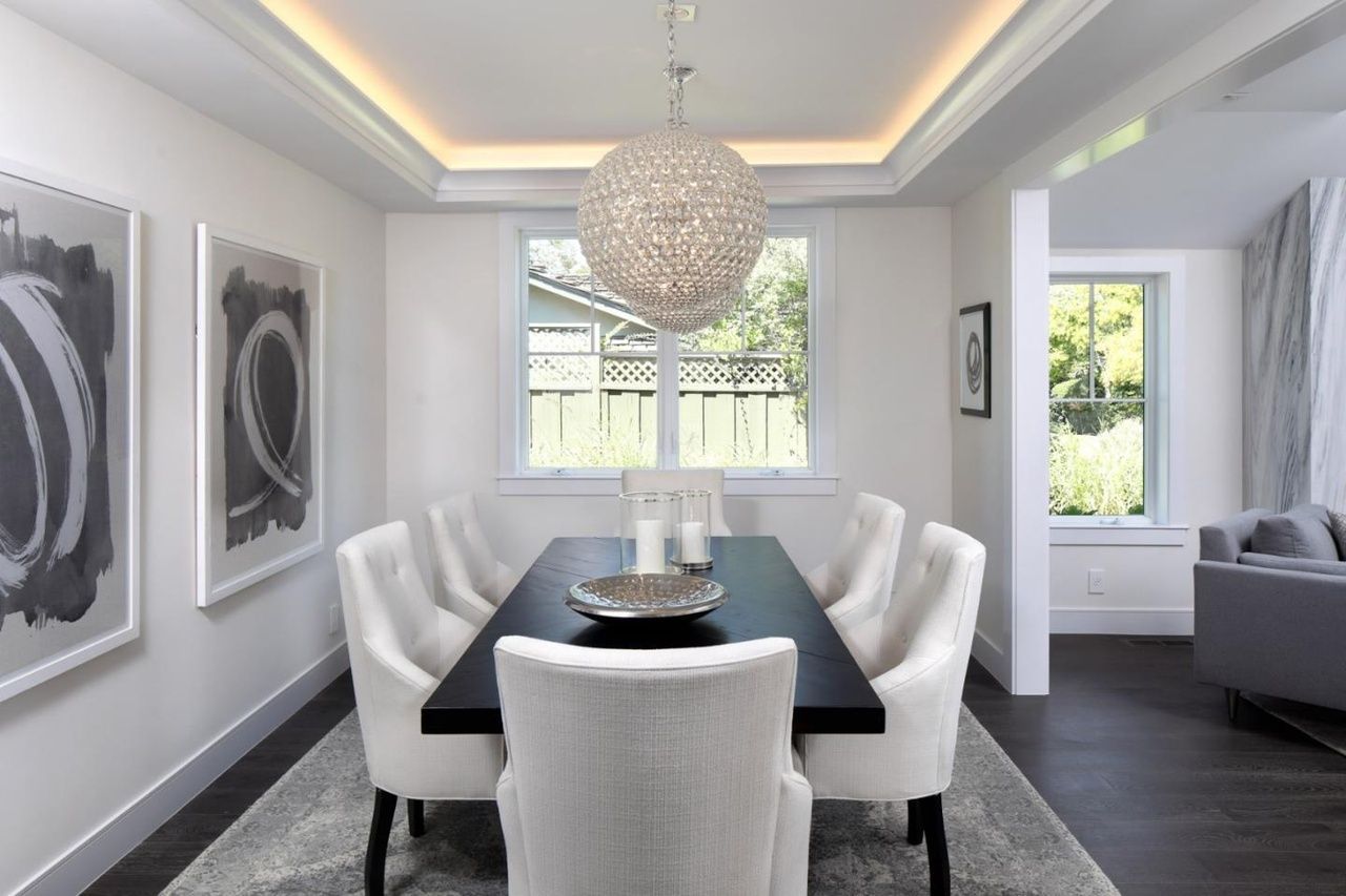 A dining room with a long black table and white chairs