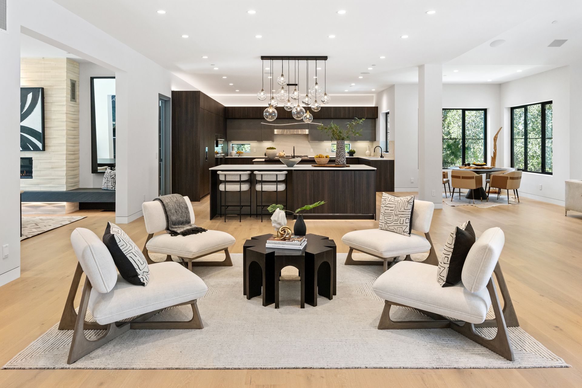 A living room with a lot of furniture and a kitchen in the background.