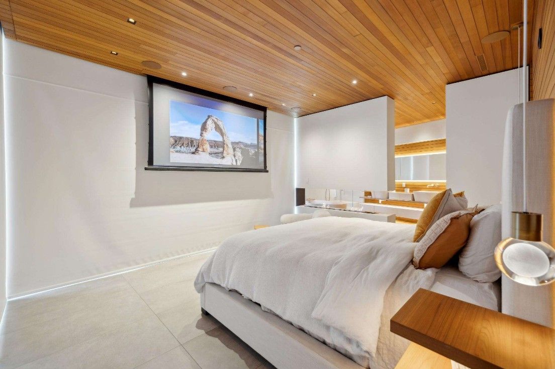 A bedroom with a large bed and a flat screen tv on the wall.