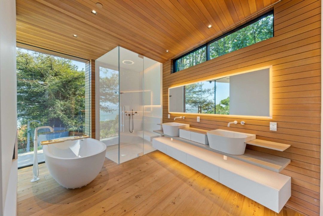 A bathroom with a bathtub , sinks , mirrors and a walk in shower.