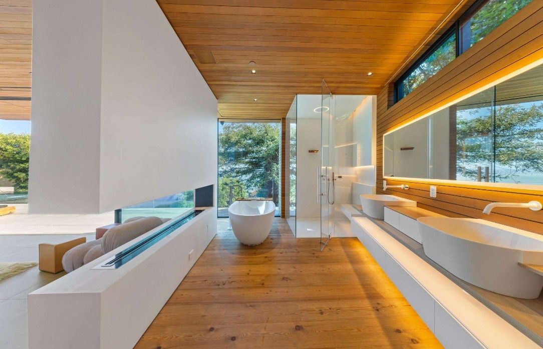 A bathroom with a tub , sinks , mirrors and a fireplace.