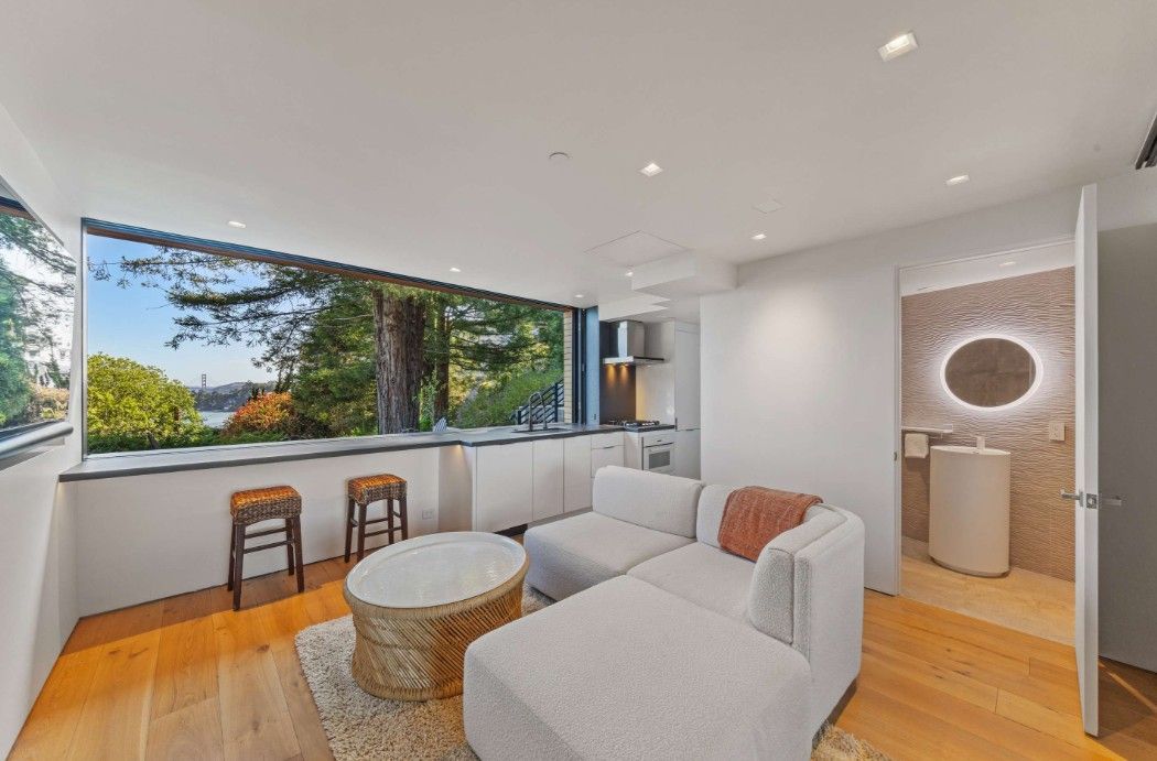 A living room with a couch , coffee table , stools and a large window.
