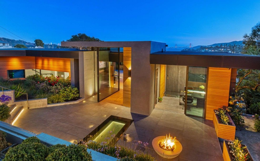 An aerial view of a modern house with a fire pit in front of it.