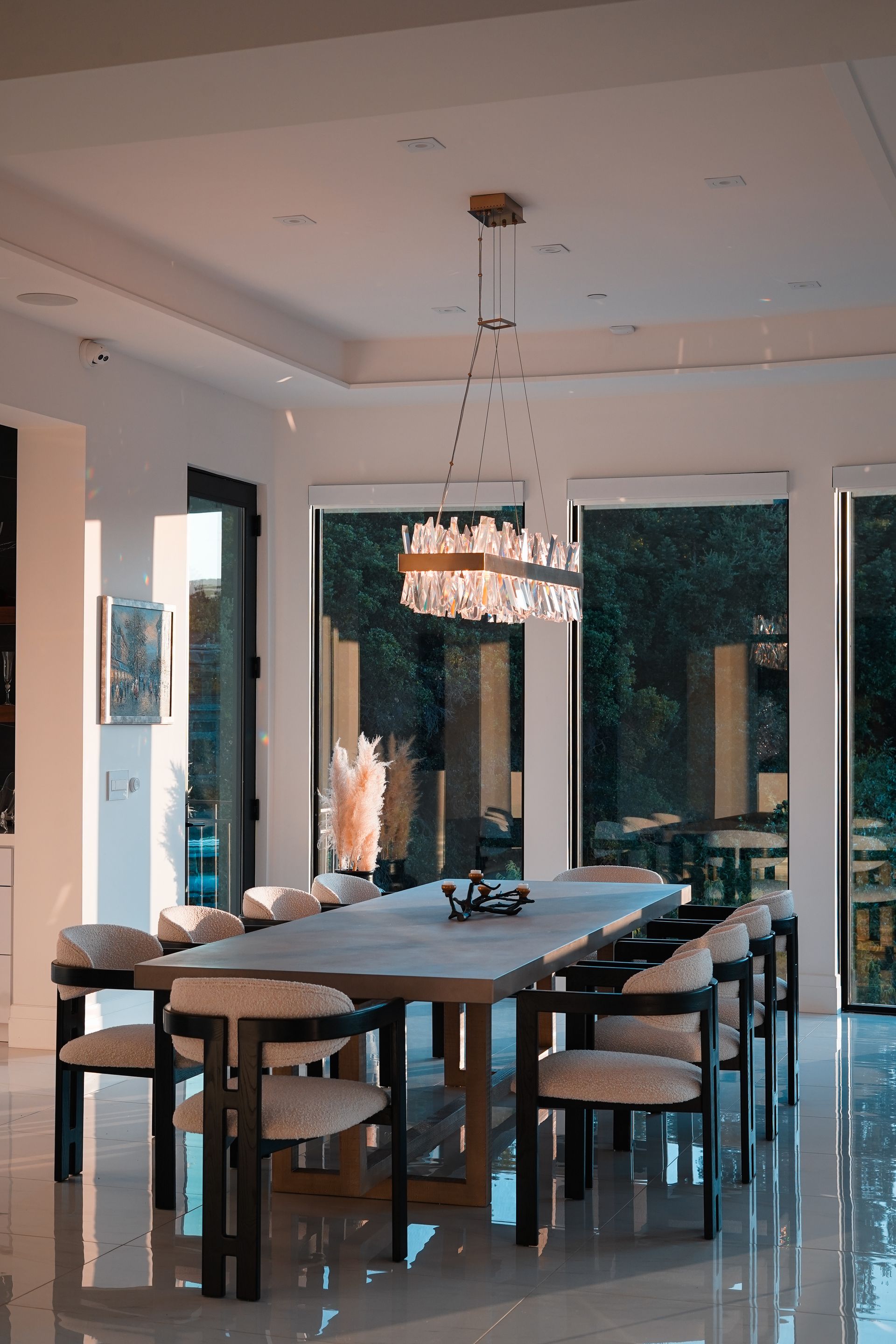 A dining room with a long table and chairs and a chandelier hanging from the ceiling.
