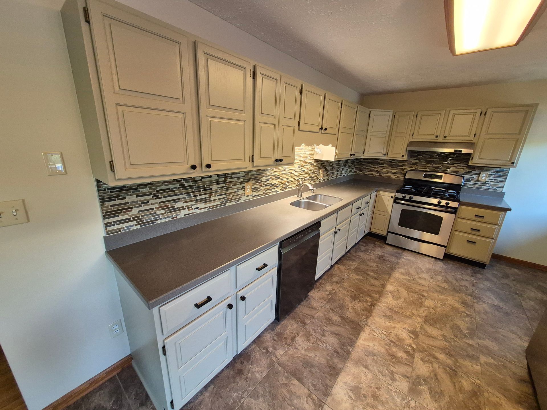 Kitchen with beige cabinets, gray countertops, and a tile backsplash.
